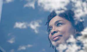 smiling woman in window looking at clouds