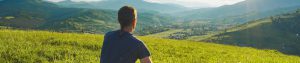 man sitting on hillside looking out